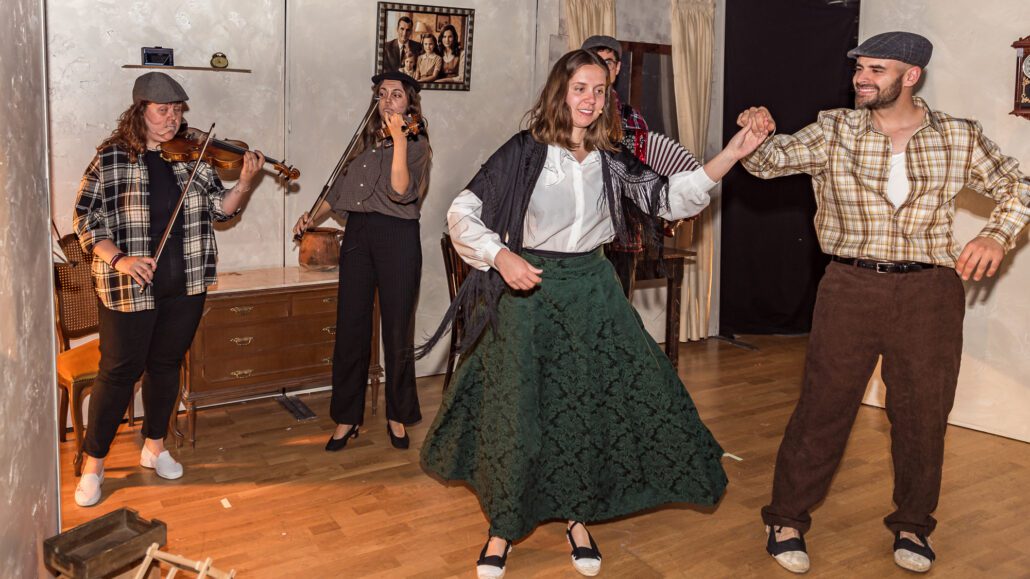 Una parella balla mentre dues noies toquen dos violins