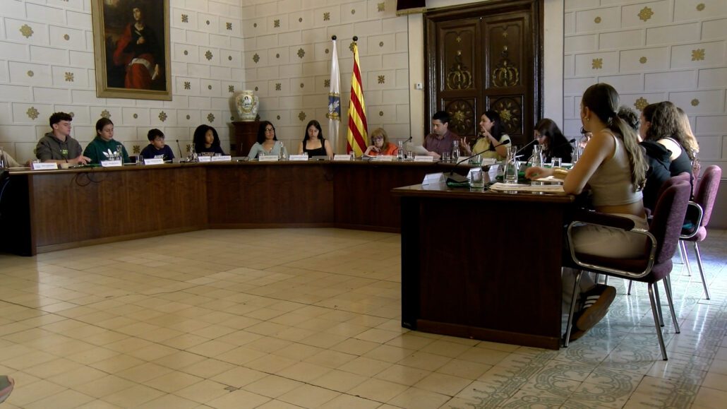 Joves asseguts en semicercle en una sala gran