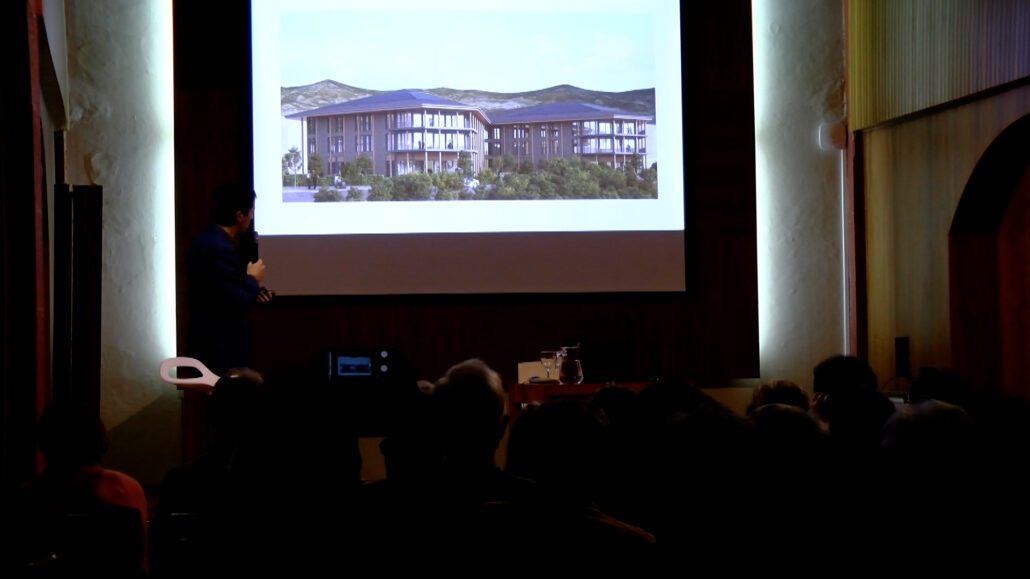 Edifici en 3D en una pantalla, en una sala en penombra