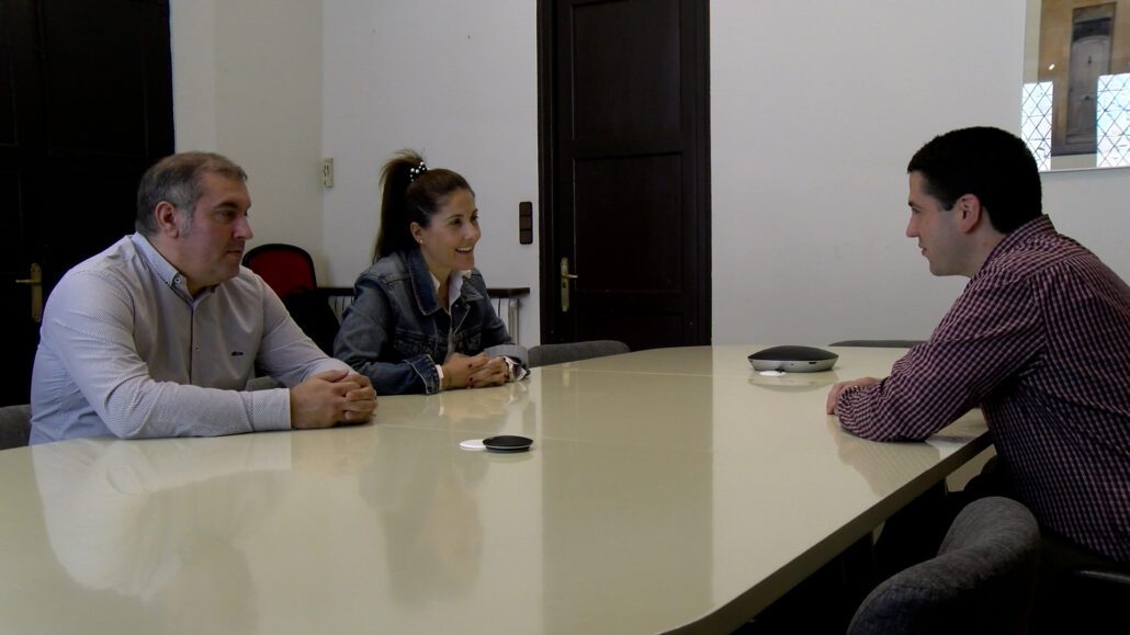 Tres persones, dos homes i una dona, asseguts al voltant d'una taula