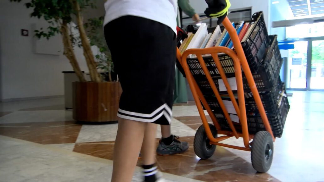 Un jove carregant llibres en un carretó