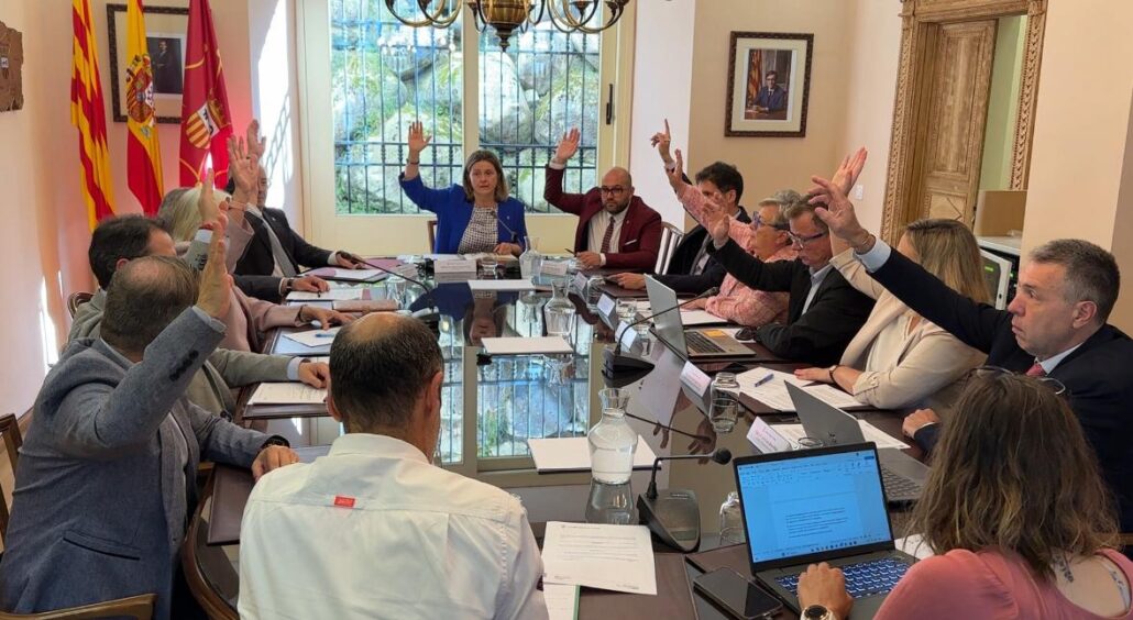 Persones assegudes al voltant d'una taula amb les mans alçades