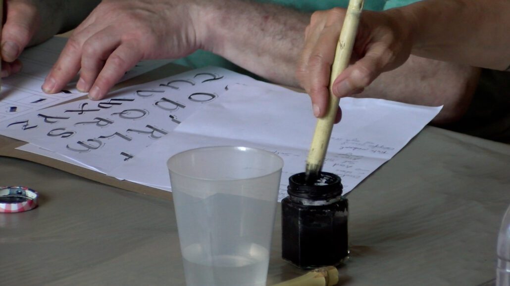 UNa persona mullant un pincell en tinta abans de començar a escriure