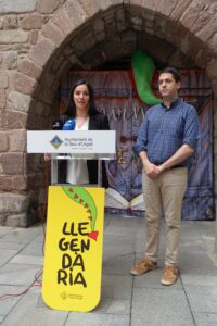 Un home i una dona davant un faristol amb un cartell de Llegendària