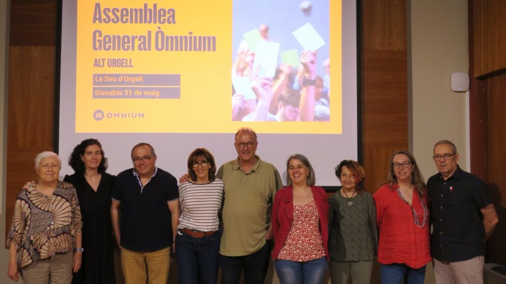 Un grup de persones davant un cartell de l'assemblea d'Òmium Alt Urgell