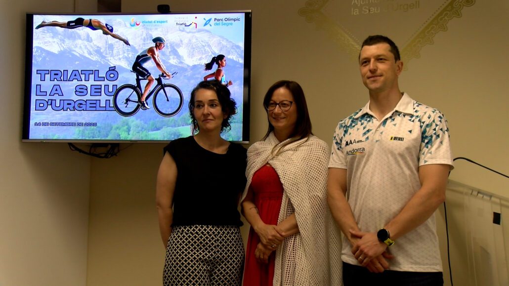 Tres persones durant amb un cartell del campionat del triatló