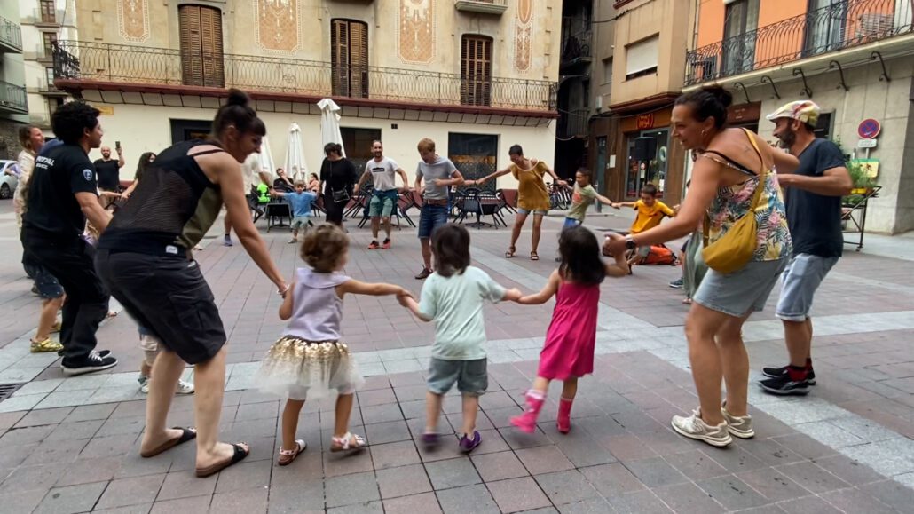 Adults i infants ballant en una plaça